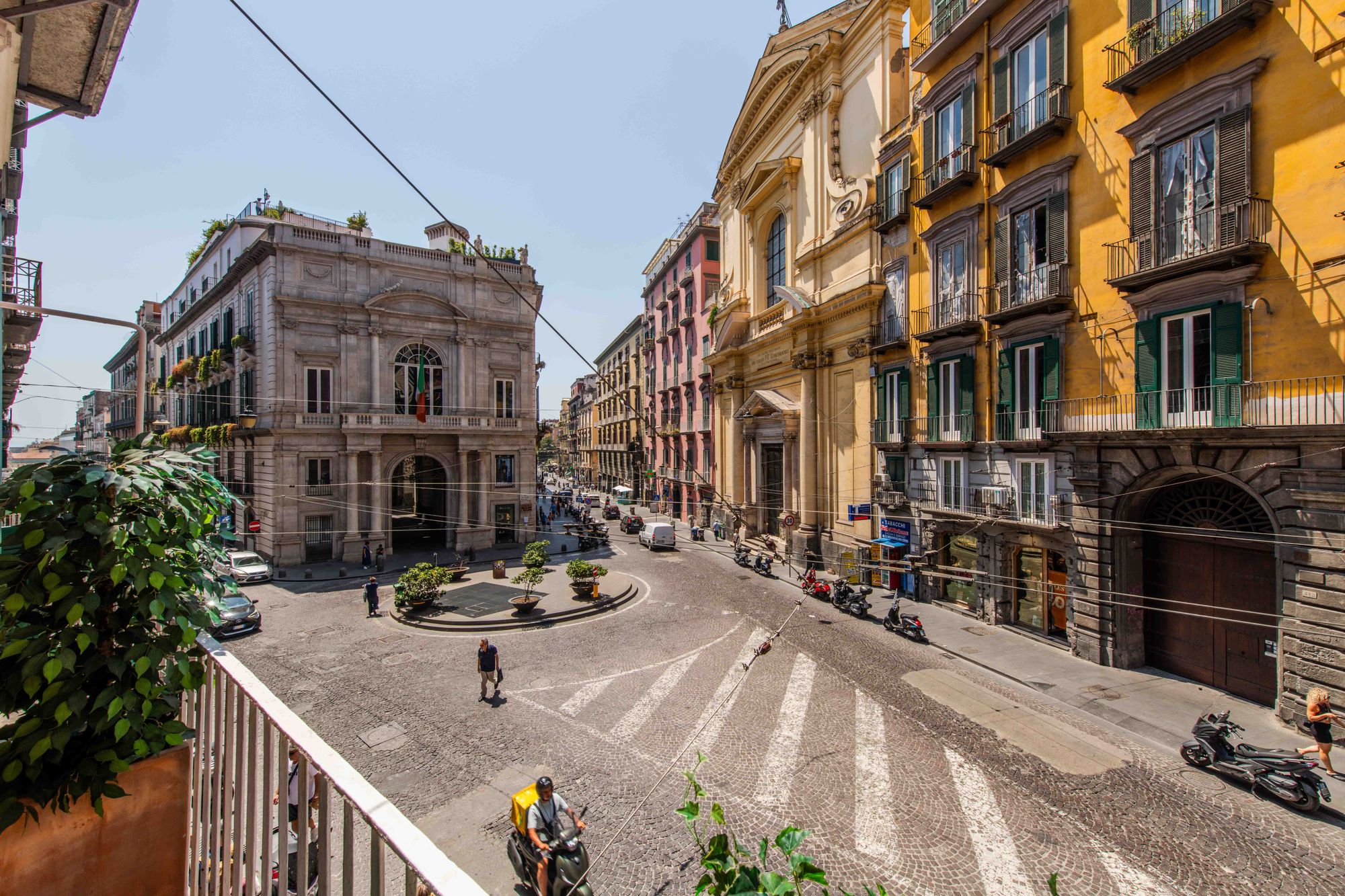 Vista panoramica dal balcone su piazza e palazzi storici napoletani con facciata di chiesa e edifici color giallo e rosa - Toledo16 Luxury Suites Napoli