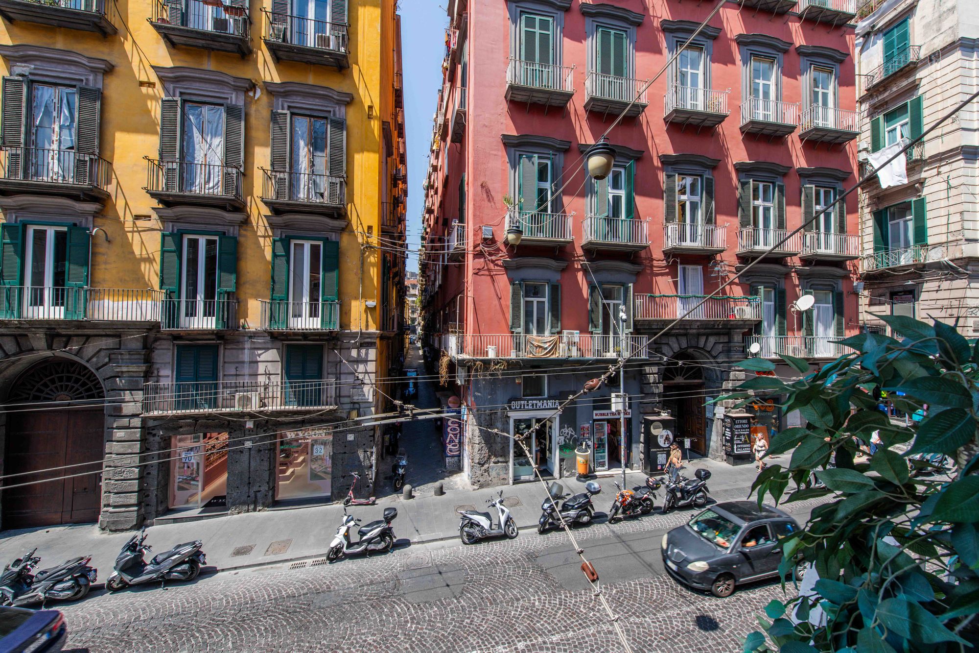 Vista dal balcone su Via Toledo e i vicoli del centro storico di Napoli, palazzi gialli e rossi, balconi in ferro battuto e scooter parcheggiati - Toledo16 Luxury Suites Napoli