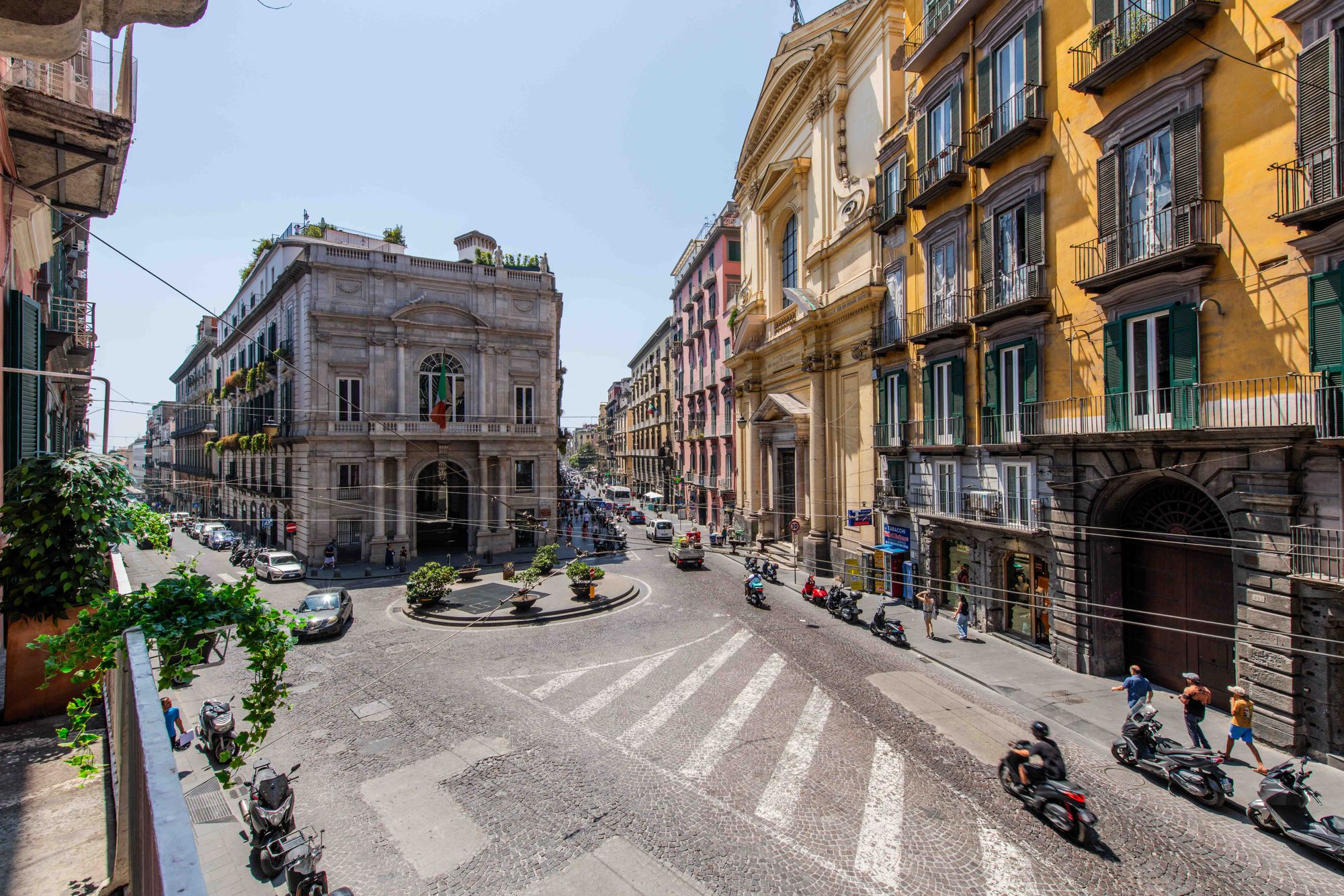 Vista panoramica dal balcone sulla piazza con edifici storici, facciata di chiesa barocca e strada lastricata di Napoli - Toledo16 Luxury Suites Napoli
