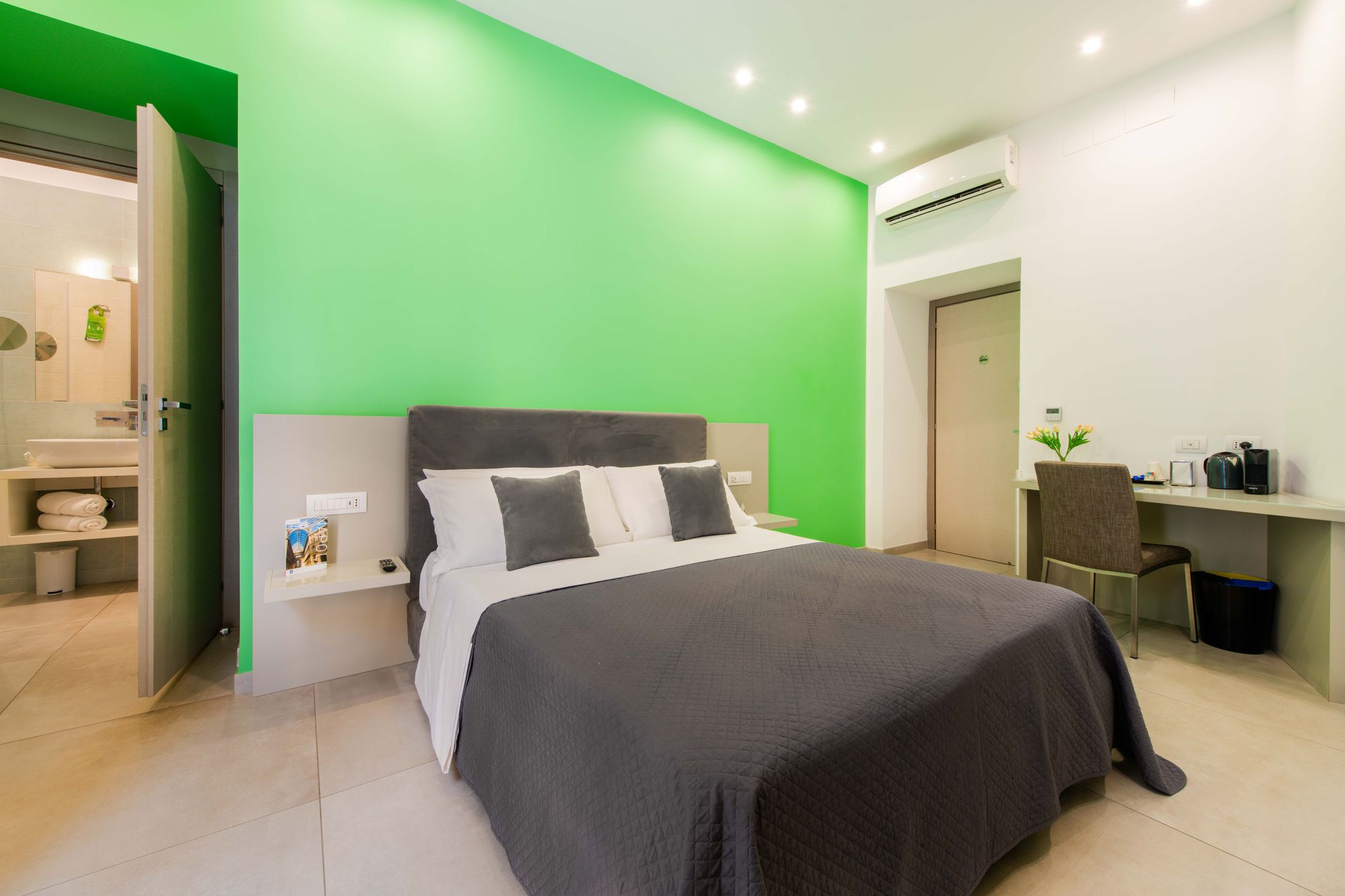 Camera con parete verde smeraldo, testiera in velluto grigio, comodino sospeso e affaccio sul bagno con lavabo - Toledo16 Luxury Suites Napoli