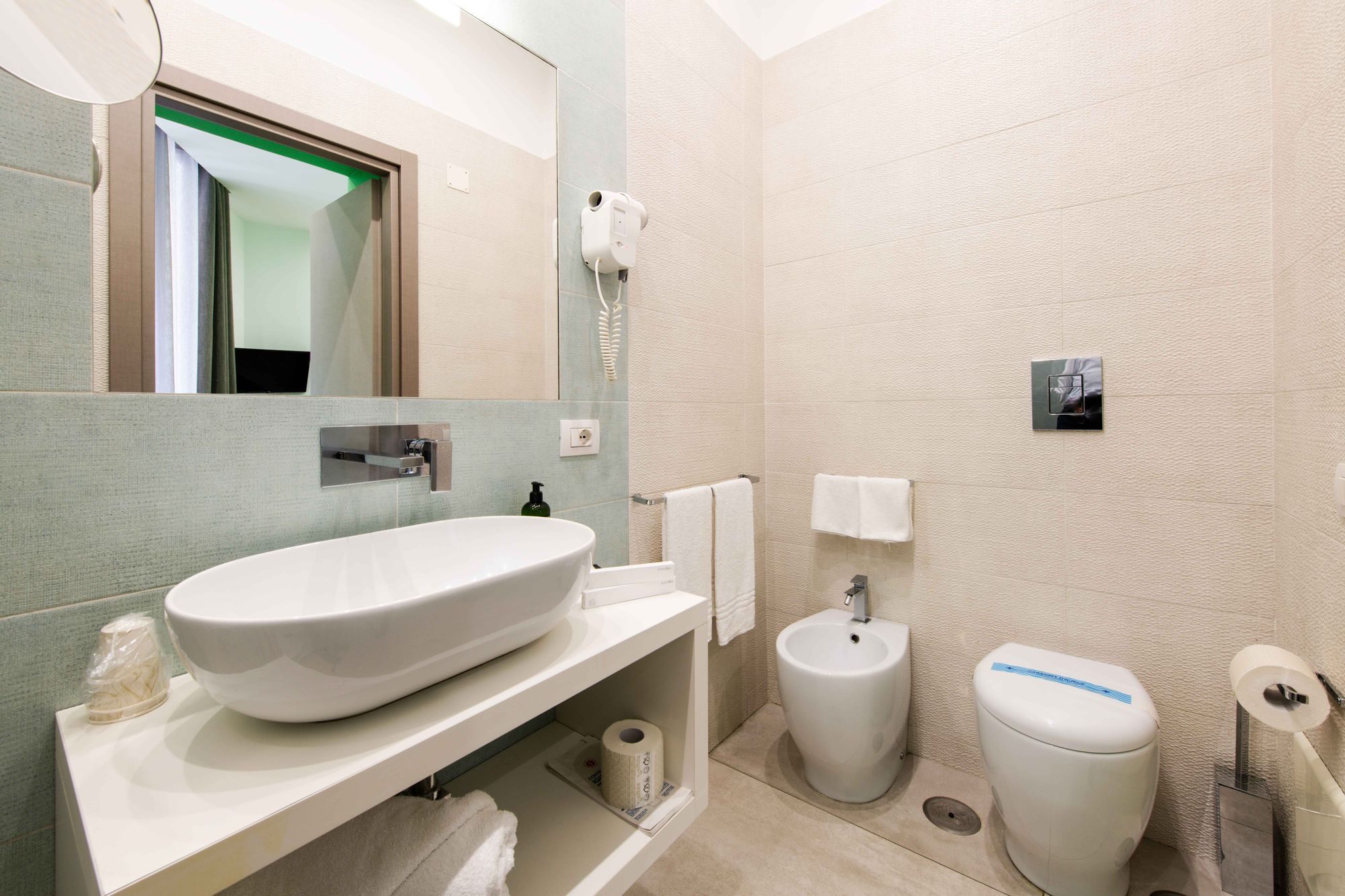 Bagno con lavabo ovale, bidet e WC con pulsante di scarico a parete, asciugamani bianchi piegati - Toledo16 Luxury Suites Napoli