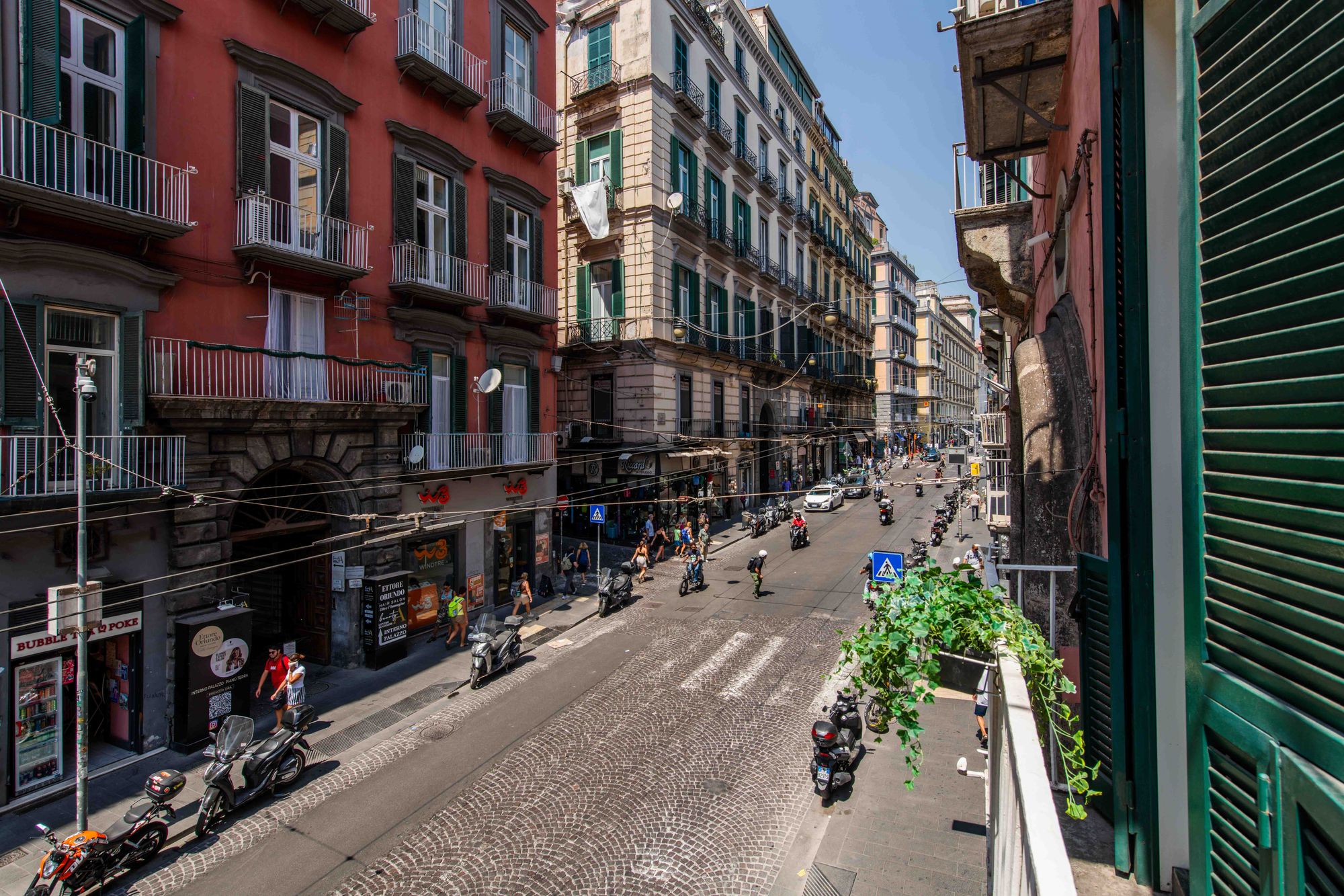 Vista panoramica dal balcone su Via Toledo nel centro di Napoli, con palazzi rossi e negozi - Toledo16 Luxury Suites Napoli