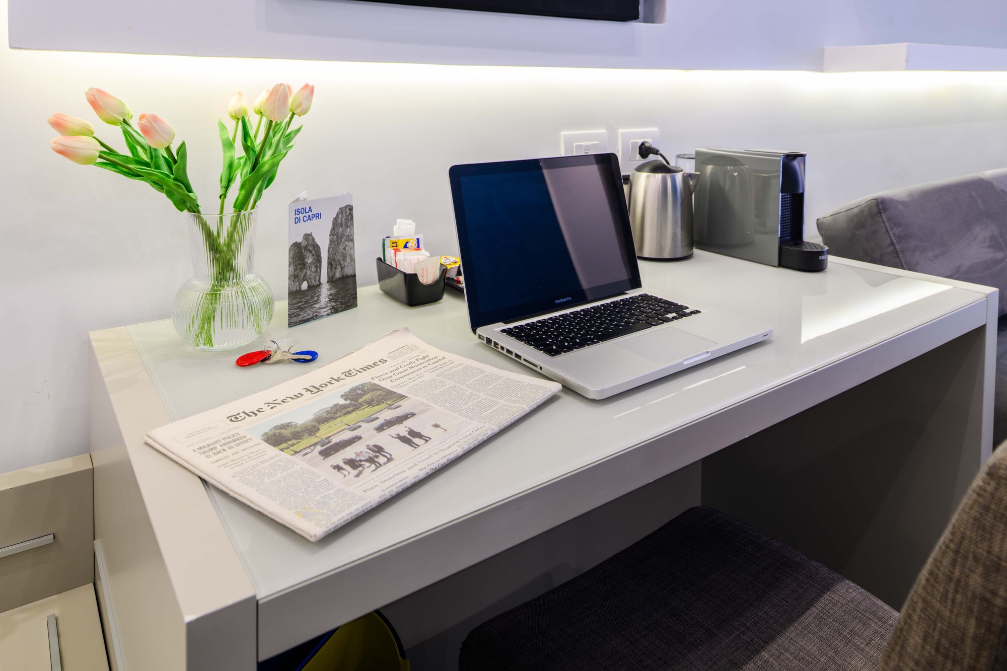 Scrivania con laptop MacBook Pro, quotidiano, tulipani e guida dell'Isola di Capri - Toledo16 Luxury Suites Napoli