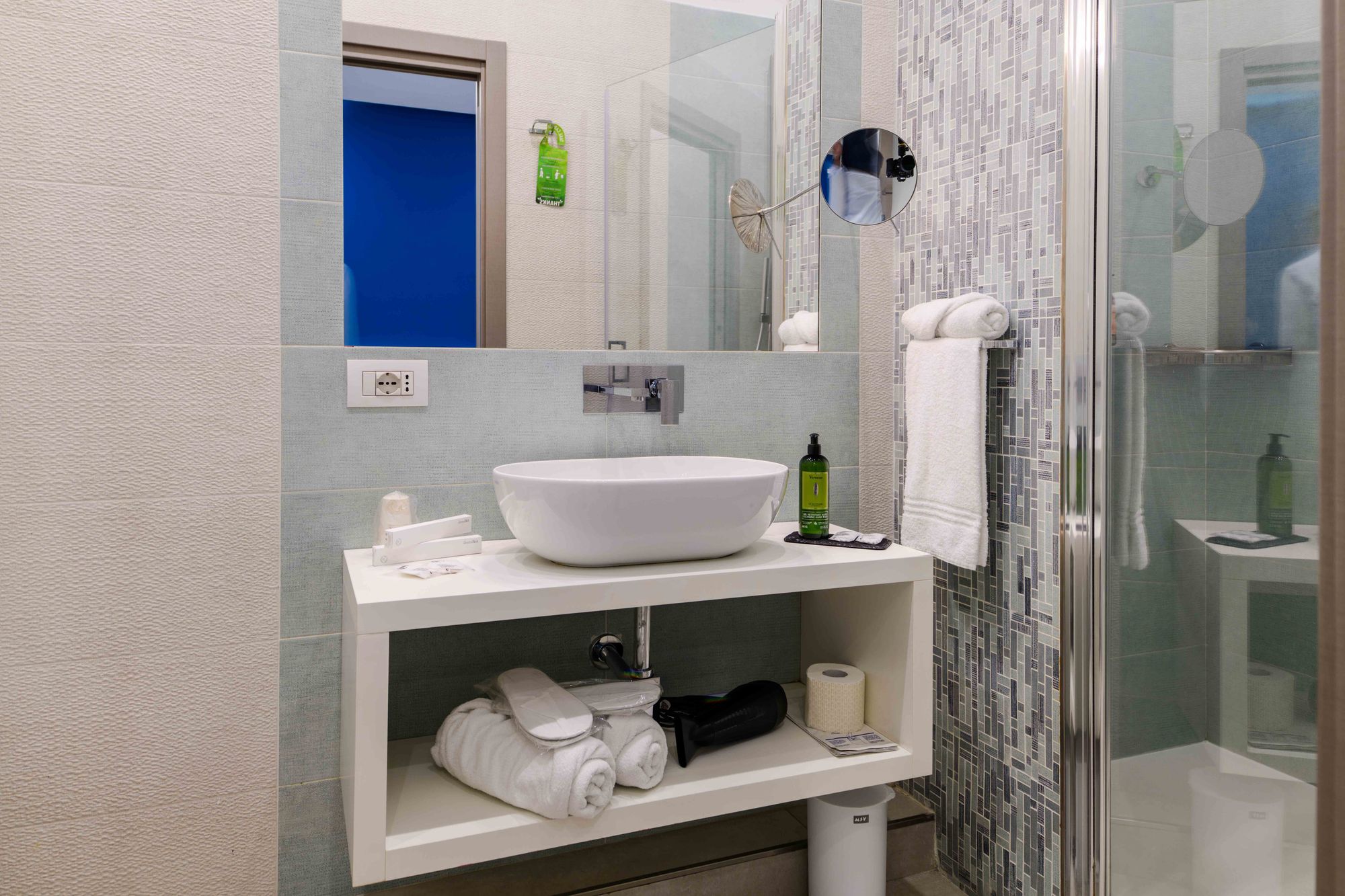 Bagno della suite con lavabo d'appoggio bianco, specchio con specchietto ingranditore e doccia con piastrelle a mosaico verde - Toledo16 Luxury Suites Napoli