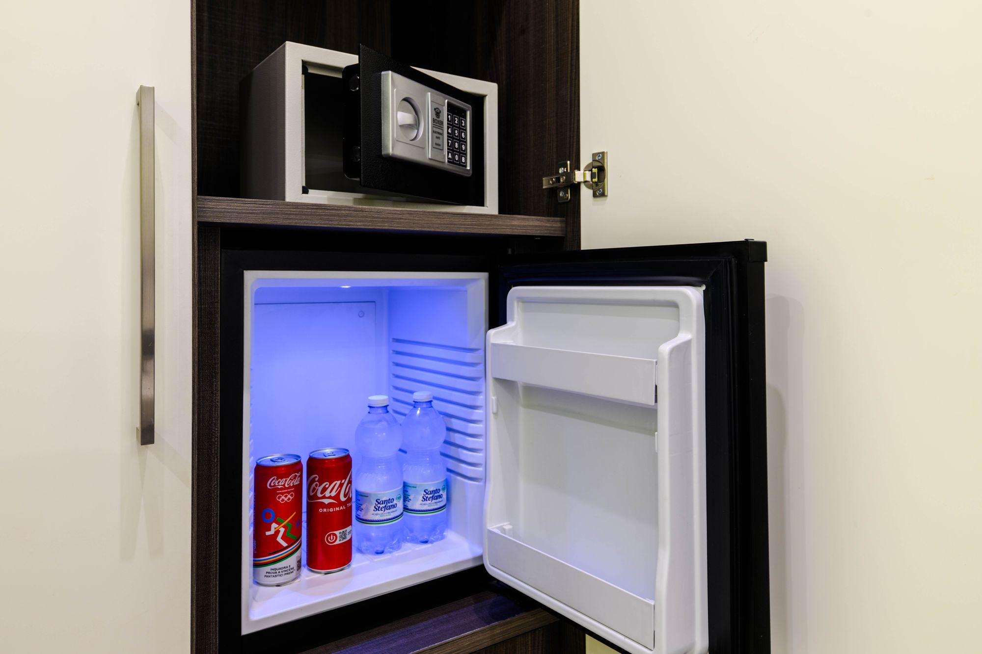 Minibar aperto con lattine di Coca-Cola e bottiglie d'acqua Santo Stefano, cassaforte elettronica nel vano superiore - Toledo16 Luxury Suites Napoli