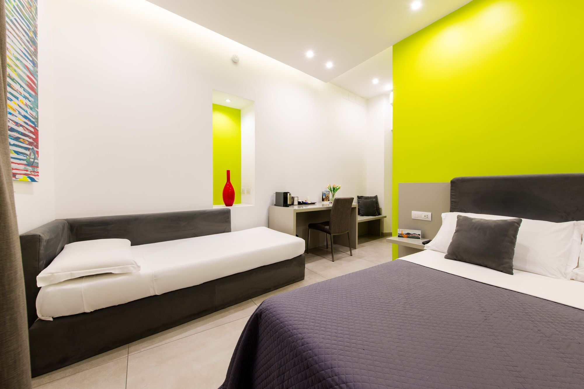 Vista della camera tripla con letto singolo ad angolo, letto matrimoniale con copriletto viola e scrivania su parete verde lime, B&B Napoli centro - Toledo16 Luxury Suites Napoli