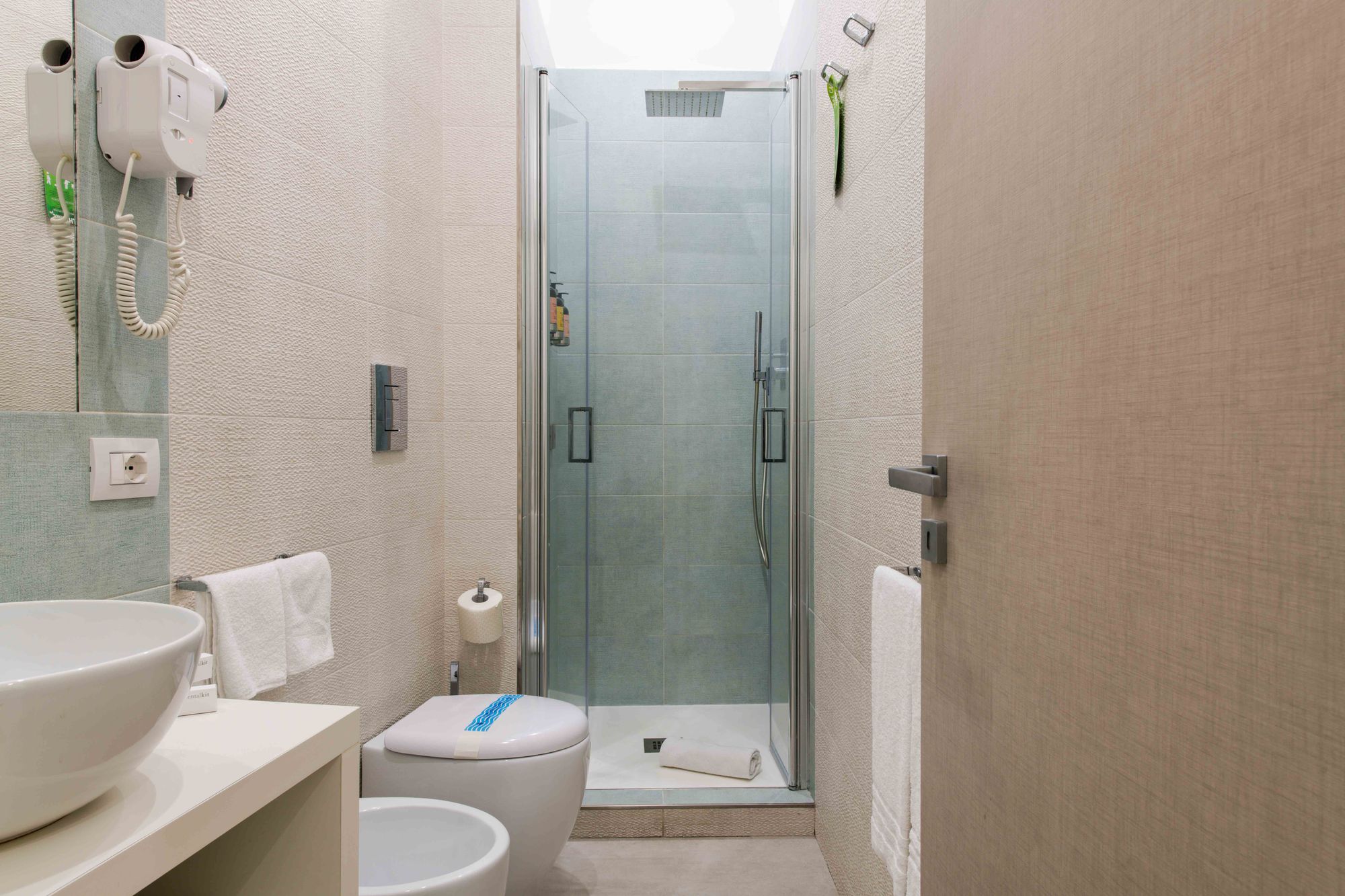 Bagno visto dalla porta d'ingresso con box doccia in vetro sul fondo, sanitari bianchi e lavabo a catino, B&B Napoli - Toledo16 Luxury Suites Napoli