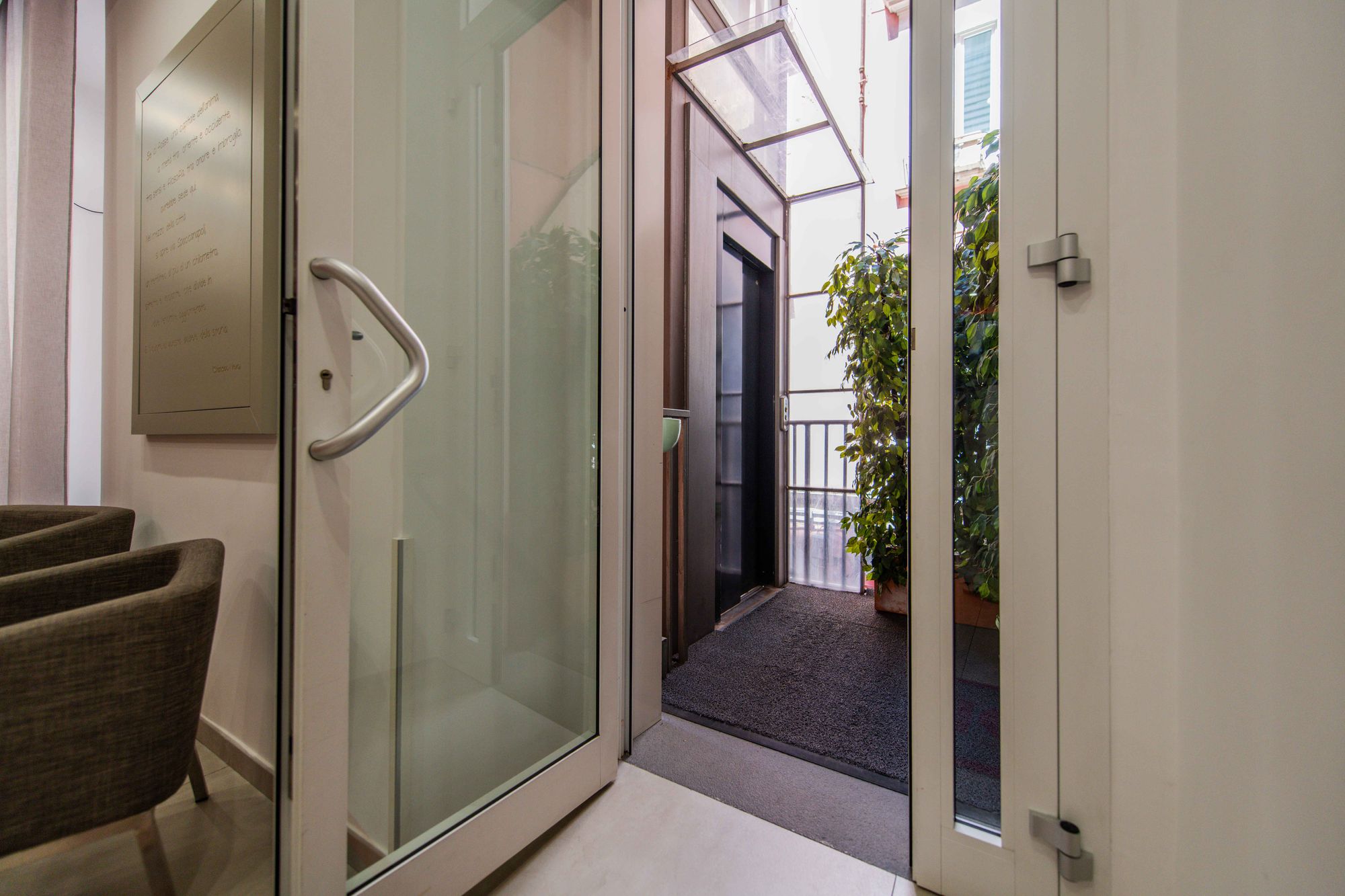 Porta a vetri dell'ingresso con self check-in autonomo, su ballatoio con piante e ringhiera in ferro - Toledo16 Luxury Suites Napoli