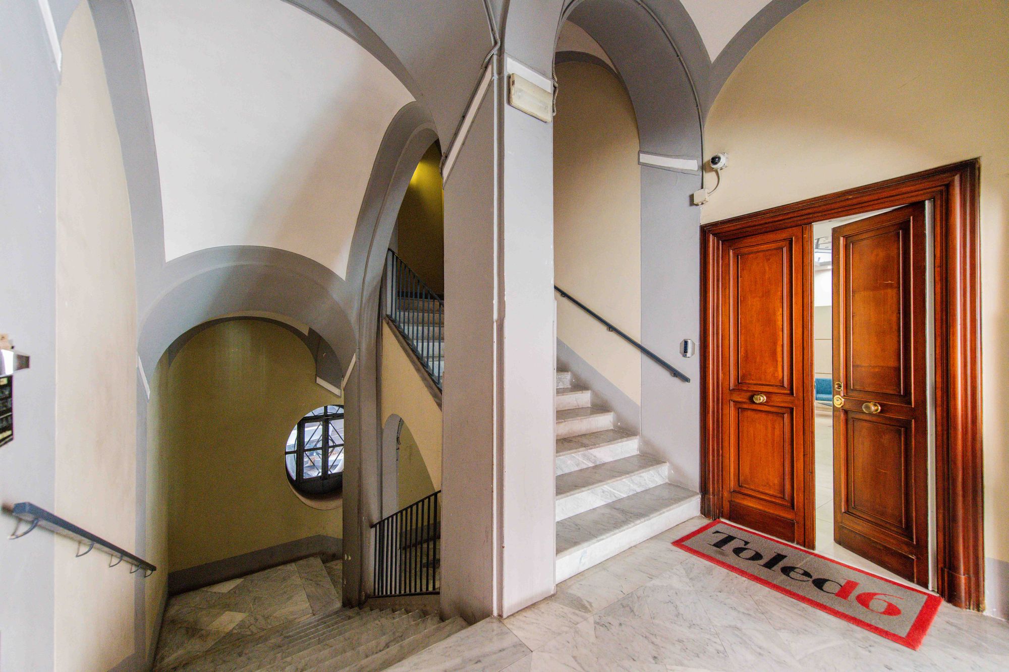 Ingresso con soffitti a volta, scala in marmo e porta in legno con tappeto personalizzato Toledo16 - Toledo16 Luxury Suites Napoli, Via Toledo 16, palazzo storico nel centro di Napoli