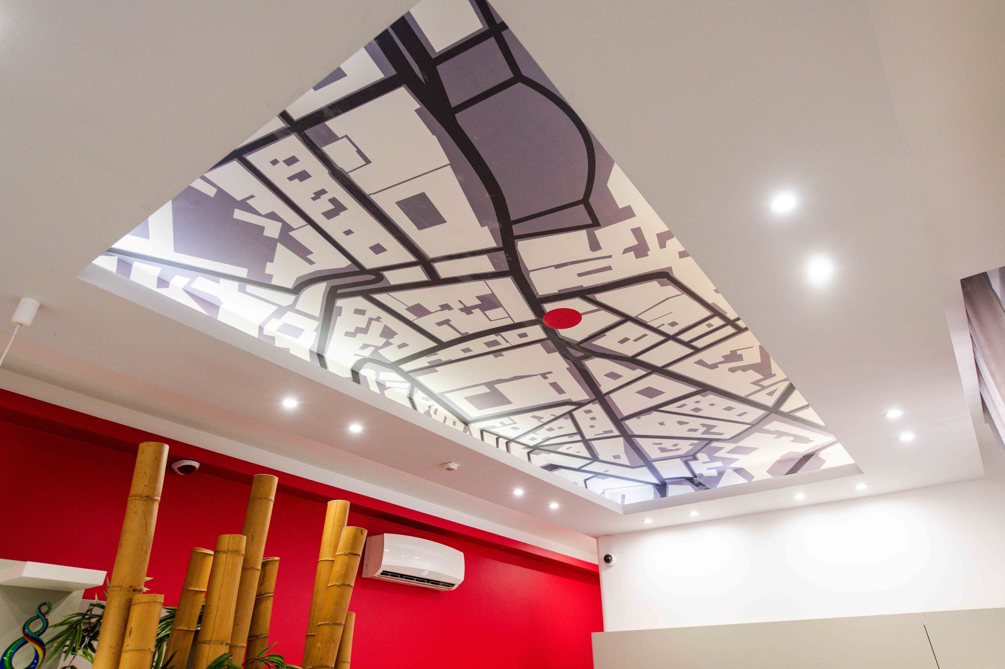Soffitto della reception con decorazione a mappa stradale di Napoli, parete rossa e canne di bambù, Toledo16 Luxury Suites Napoli